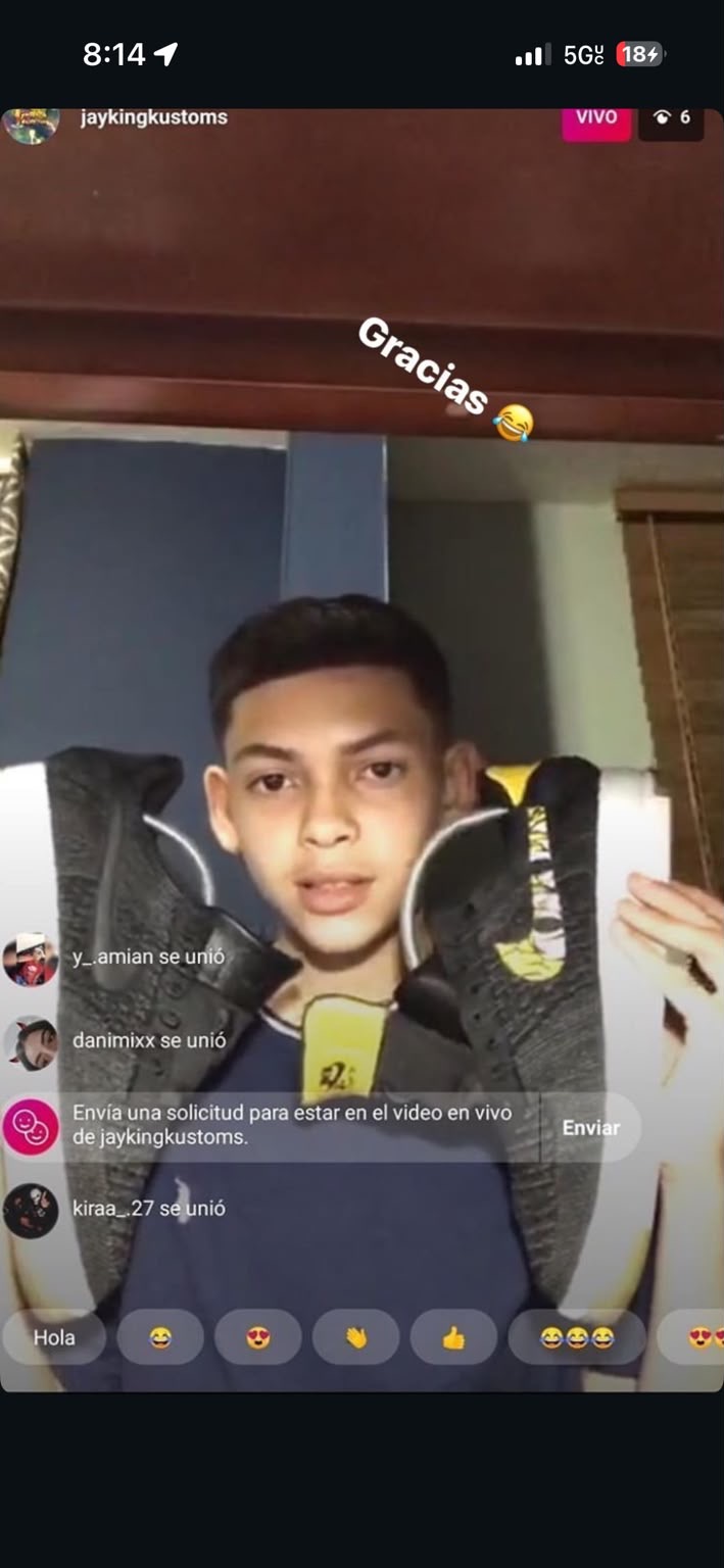 Ryan as a teenager holding up a pair of custom black sneakers during a live video